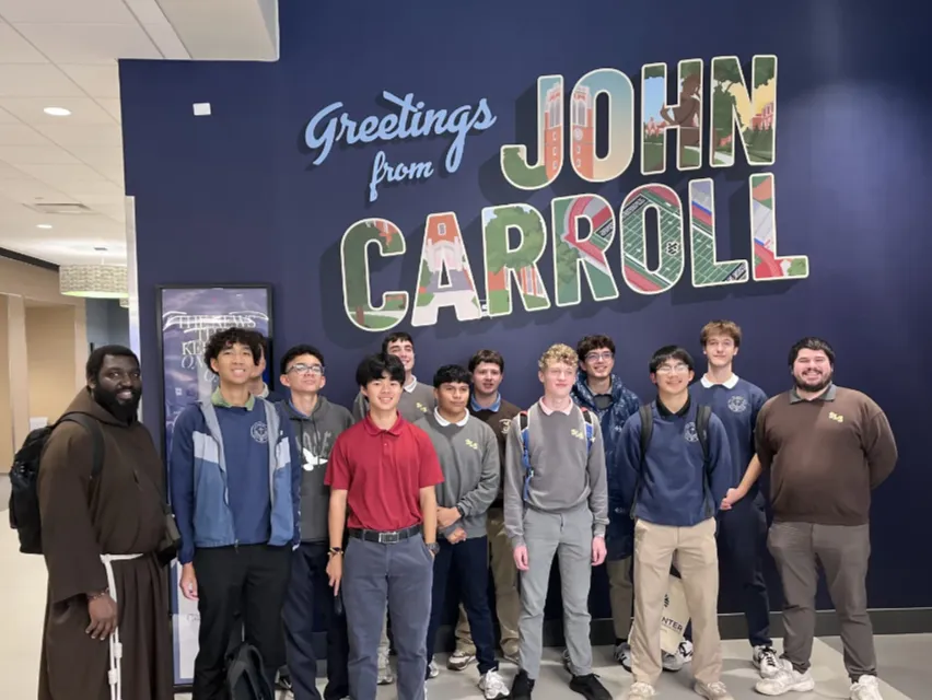 3 students in front of a cross